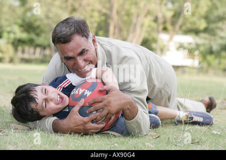 Ältere Mann und sein Enkel spielen mit einem Ball im park Stockfoto