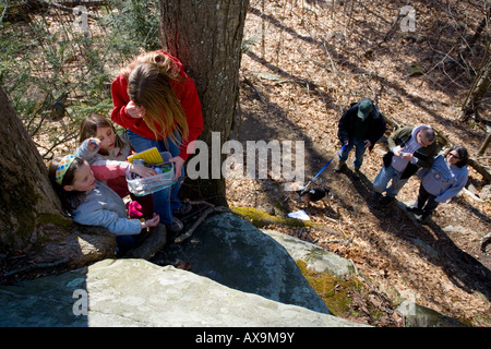 Ein GPS-Handgerät benutzt, finden einen Geocache oder Geo-Cache, der eine Wander-Aktivität ist Boxen wo Menschen suchen eine Familie Stockfoto