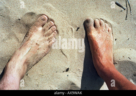 Männliche und weibliche Füße im Sand Stockfoto
