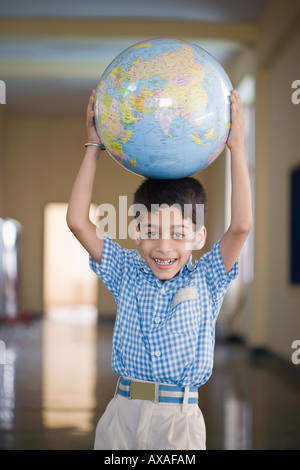 Porträt von Schuljunge hält einen Globus über seinem Kopf Stockfoto
