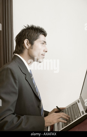 Seitenansicht eines Unternehmers mit einem Laptop auf dem Stehpult Stockfoto