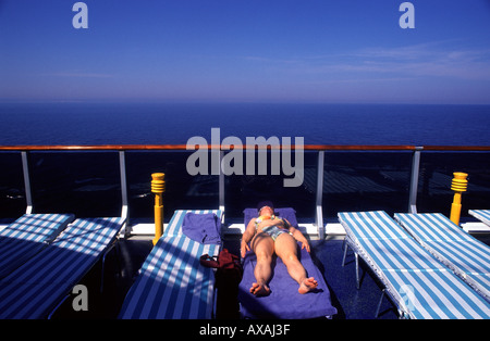 Frau auf einem Liegestuhl auf dem Passagierdeck des Liners Sonnenbaden Kreuzfahrtschiff Stockfoto