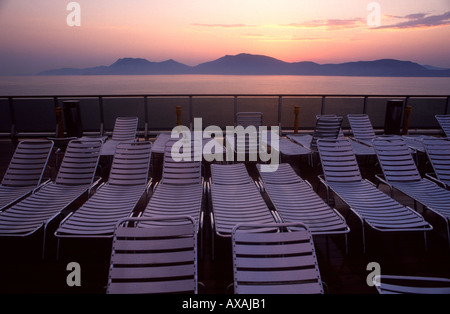 Stapel von leeren Kunststoff Chaise Lounge Stühle auf einem PKW-Deck eines Kreuzfahrtschiffes Liner bei Sonnenuntergang Stockfoto