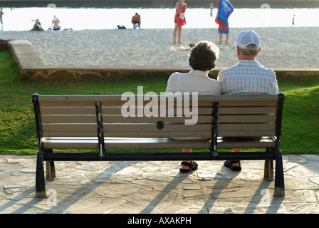 Ehepaar im Ruhestand sitzt auf einer Parkbank am Ende des Tages am Waikiki Beach Oahu Hawaii Stockfoto