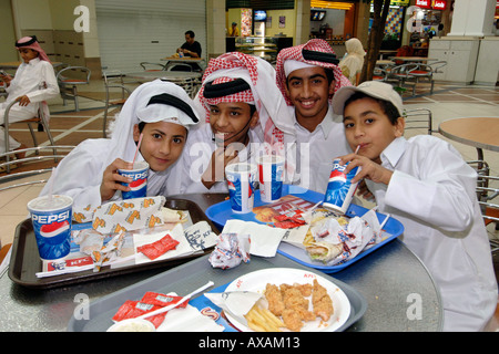 Katar Kinder in traditionellen Outfits Fastfood in einem Einkaufszentrum in Doha. Stockfoto