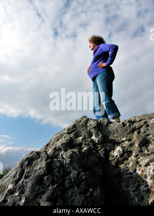 Herr junge schwangere Frau auf Felsen hält ihren Bauch Stockfoto