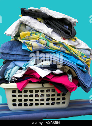Waschkorb voller Kleidung, mit einem blauen Hintergrund. Stockfoto
