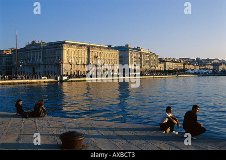 Leute sitzen auf dem Pier in den Abend Sonne, Mola Audace, Triest, Friaul, Italien, Europa Stockfoto