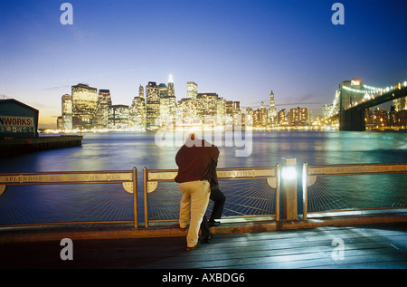 Ein paar stehen auf der Brooklyn Bridge, Blick auf die beleuchtete Skyline, Manhattan, New York, USA, Amerika Stockfoto