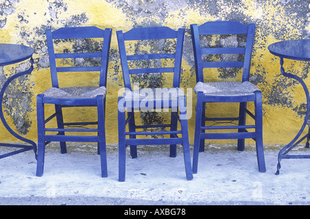 Drei blaue Stühle gegen gelbe Wand Nisyros Griechenland Stockfoto