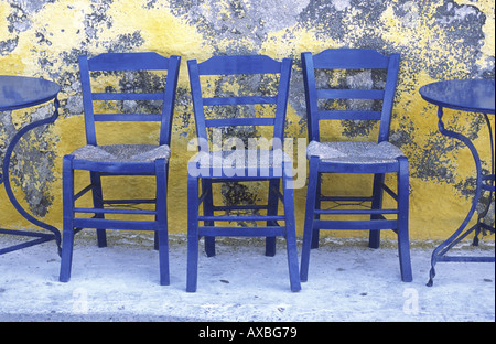 Drei blaue Stühle gegen gelbe Wand Nisyros Griechenland Stockfoto