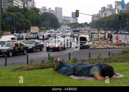 Obdachloser schläft auf einem Grünstreifen in der Mitte der Avenida 9 de Julio (A) Stockfoto