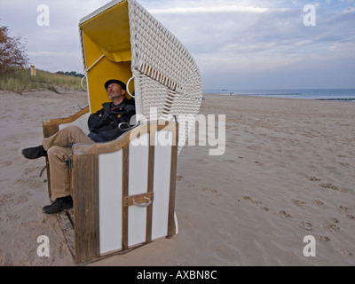 Herr Mann in warme Kleidung sitzt im Strandkorb am Strand im Herbst-Winter in Heringsdorf auf der Insel Usedom-Deutschland Stockfoto