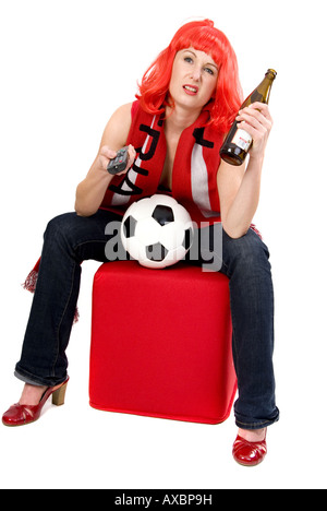weibliche Fußball-Fan mit einer roten Perücke, eine Flasche Bier und Fernbedienung ein Fußballspiel ansehen Stockfoto