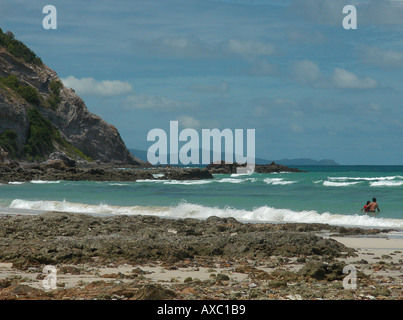 Zerklüftete Küstenlinie mit wogenden Wellen, Surfen, junges Paar waten, Algen am Strand, Koh Larn, auch bekannt als Koralleninsel, Pattaya, Thailand Stockfoto