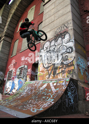 BMX-Fahrer nach dem Sprung von der Rampe vor Wand mit Graffiti unter der Manhattan-Bridge, USA, Manhatten, New York Stockfoto