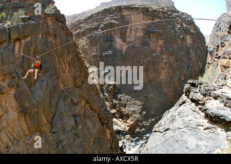 Ein Wanderer durchqueren eine Seilrutsche (alias Flying Fox) auf die Via Ferrata Wandern im Snake Canyon im Jebel Akhdar Gebirge im Oman. Stockfoto