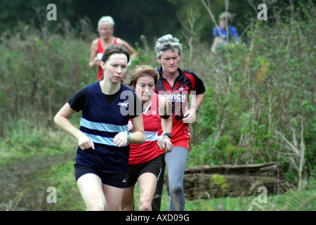 Eine Gruppe von drei cross Country Läufer Rennen durch sumpfige land Stockfoto