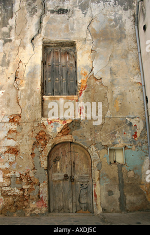 Verschlechtert sich rissig und teilweise bemalte Wand mit Holztür shuttered Fenster und Fallrohr Chania Kreta-Griechenland Stockfoto