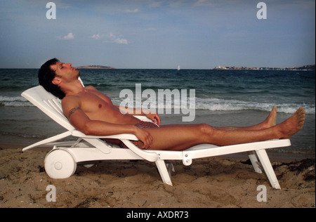 Mann Sonnenterrasse am Strand Stockfoto