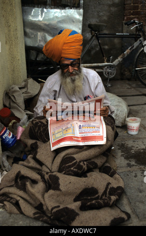 Alten Sikh lesen Papier auf Asphalt, Delhi Stockfoto