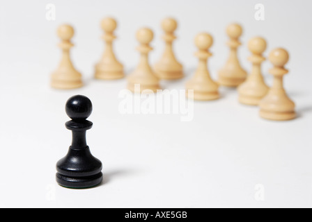 Schach, steht einem schwarzen Bauern vor einer Gruppe von weißen Bauern, Symbol für soziale Ausgrenzung, Konfrontation Stockfoto