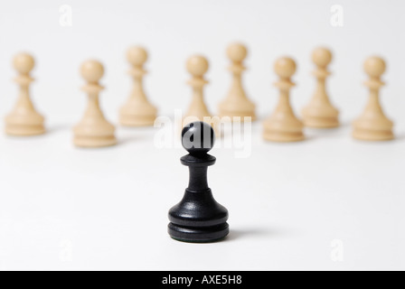 Schach, steht einem schwarzen Bauern vor einer Gruppe von weißen Bauern, Symbol für soziale Ausgrenzung, Konfrontation Stockfoto