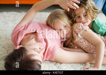 Mutter und Kinder auf Boden liegend in Wohnzimmer, Porträt Stockfoto