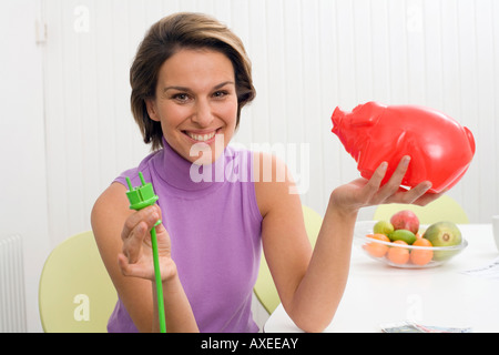 Frau mit grünen Stecker und Sparschwein Stockfoto