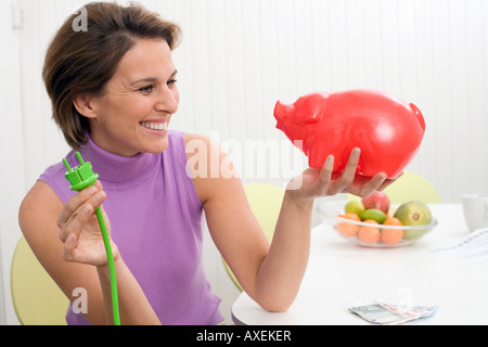 Frau mit grünen Stecker und Sparschwein Stockfoto