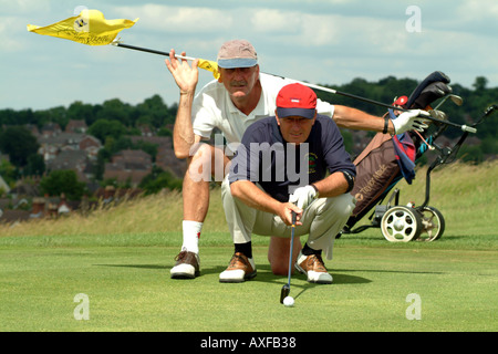 Senior Golfer mit Caddie Beratung auf einer grünen auf Andover Golfplatz Hampshire England UK Europe Stockfoto