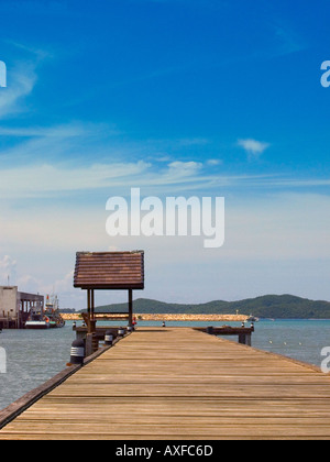 Holzsteg mit rotem Ziegeldach Tierheim, Stein gebaut Wellenbrecher und weit entfernten grünen Hügel sichtbar hinter, Ban Phe, Rayong, Thailand Stockfoto