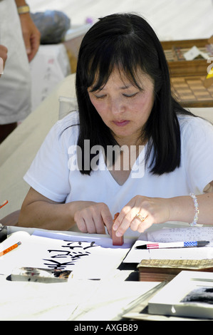 Japanisches amerikanisches weibliche schreibt amerikanischen Namen auf Japanisch auf einem Handwerk Messe Stockfoto