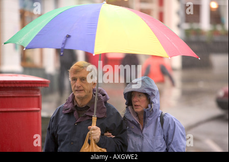 ein paar bergende unter einem Regenschirm im Regen, Stockfoto