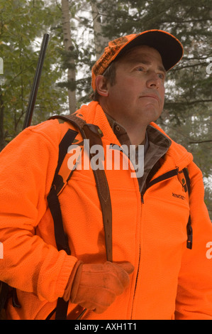 PORTRÄT VON DEER HUNTER BLAZE ORANGE MIT GEWEHR AUF DEM RÜCKEN IM NÖRDLICHEN MINNESOTA NEBLIGEN WALD Stockfoto