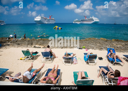 Touristen, die Sonnen auf Strandkörbe an der Uferpromenade in Georgetown auf Grand Cayman auf den Cayman Islands Stockfoto