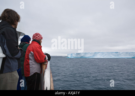 Touristen auf dem Deck eines Kreuzfahrtschiffes Schiff gerade riesige Tafeleisberge vorbei in der Antarktis. Stockfoto