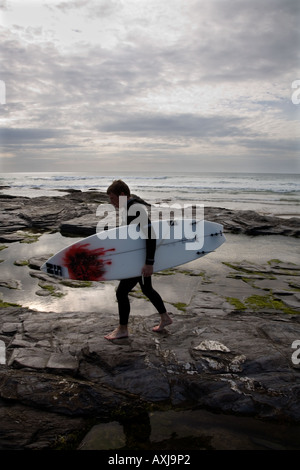 Surfer geht über die Felsen in der Bucht von Constantine. Cornwall. UK Stockfoto