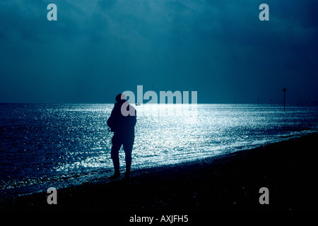 Ein Mann geht an einem Strand entlang an einem kalten Tag Stockfoto