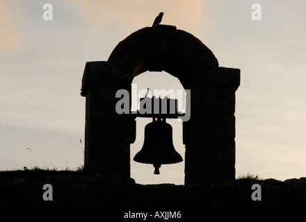 Ein Starling Sturnus Vulgaris begrüßt die Dämmerung auf einer Glocke in die Granitmauern gesetzt Stockfoto