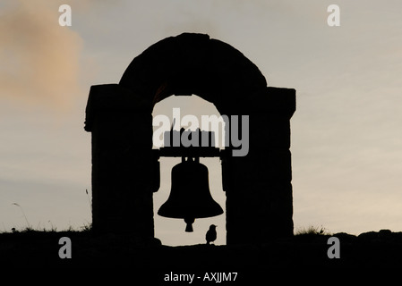 Ein Starling Sturnus Vulgaris begrüßt die Dämmerung von einer Glocke in die Granitmauern gesetzt Stockfoto