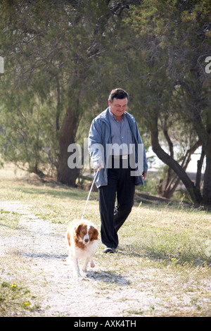 Mann zu Fuß Hund auf Weg in der Nähe von Saronida in Attika oder Atiki Griechenland EU Stockfoto