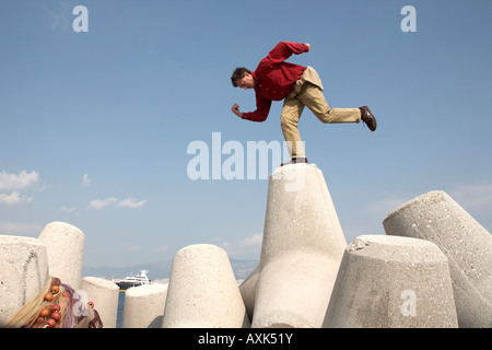 Mann in Denker Pose stehend balancieren auf Meer Betonwand Abwehrkräfte Mikrolimano Hafen von Piräus oder Pireas Athen Griechenland Stockfoto