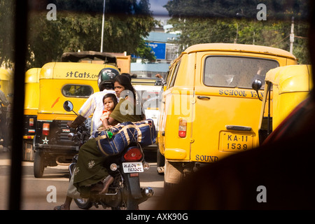 Eine Familie sitzt auf einem Motorrad unter Rikschas in der schnell wachsenden Stadt Bangalore in Südindien. Stockfoto
