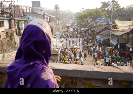 Eine verschleierte Frau Bengali blickt auf bei Käufern und Verkäufern Mühle herum in den bunten Mullick Ghat Blumenmarkt, Kalkutta. Stockfoto