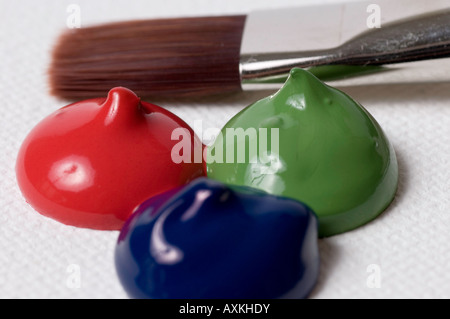 roter, grüner und blauer Farbe fällt auf einer Leinwand mit einem Pinsel in der Nähe von Stockfoto