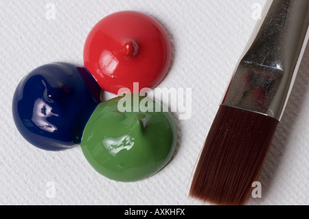 roter, grüner und blauer Farbe fällt auf einer Leinwand mit einem Pinsel in der Nähe von Stockfoto