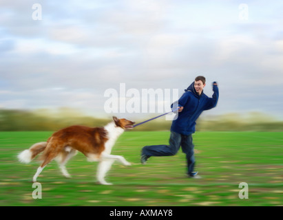Junger Mann läuft im Park mit Barsoi Hund Seitenansicht Stockfoto