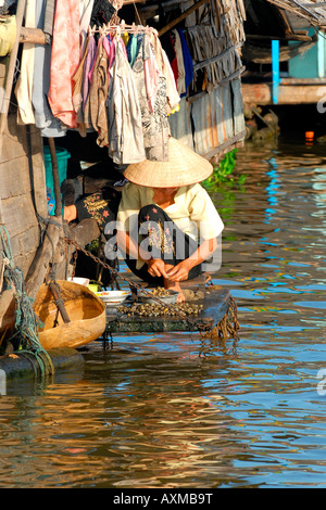 Kambodscha, Tonle Sap See, Phom Krom, hübsches junges Mädchen in Tracht auf Hausboot wäscht Wellhornschnecken zum Kochen Stockfoto