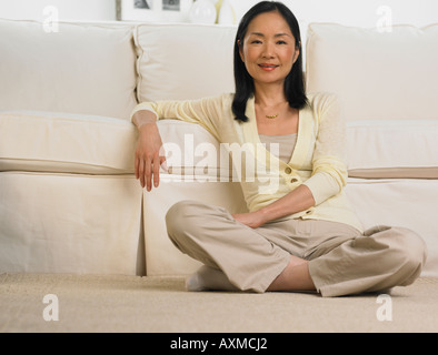 Applying Asiatin stützte sich auf das Sofa zu Lächeln Stockfoto